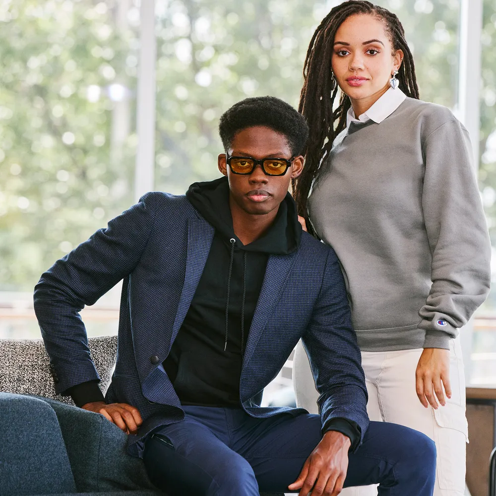 Two people in branded apparel: a navy blazer over a hoodie, and a grey crewneck sweatshirt